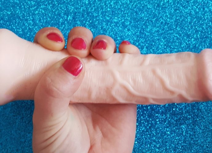 Feature photo for Lovehoney Lifelike Lover Ultra Realistic 7" Dildo review. Holding dildo over glittery blue background.